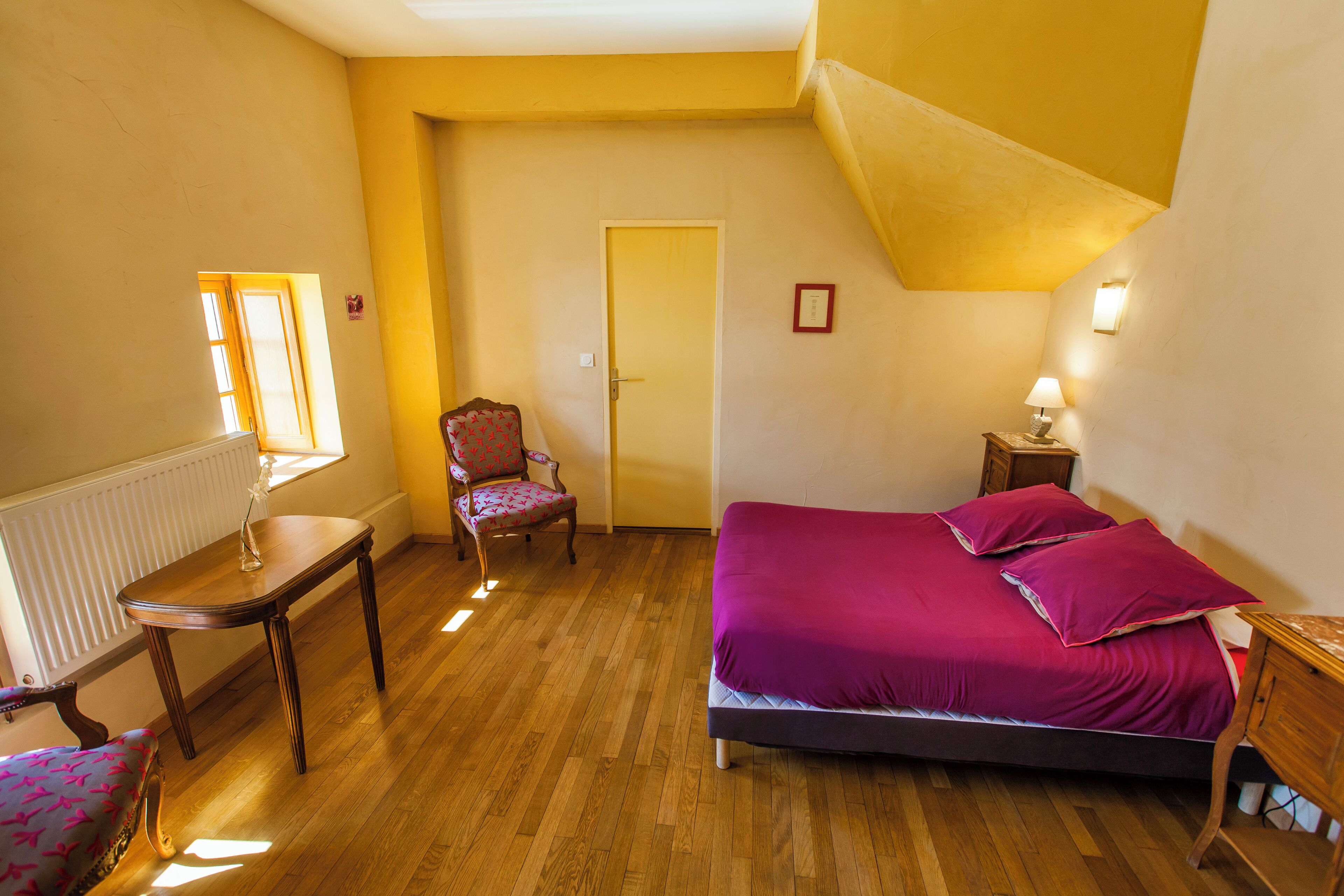 Un dormitorio con cama, una silla, una mesa y una puerta.