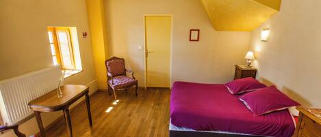 Un dormitorio con cama, una silla, una mesa y una puerta.