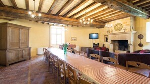 A rustic dining area with a long table, wooden chairs, and a fireplace. - Large gîte with indoor pool and sauna (Charbogne)