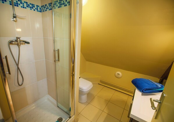 A bathroom with a glass-enclosed shower, a toilet, and a sink with a towel.
