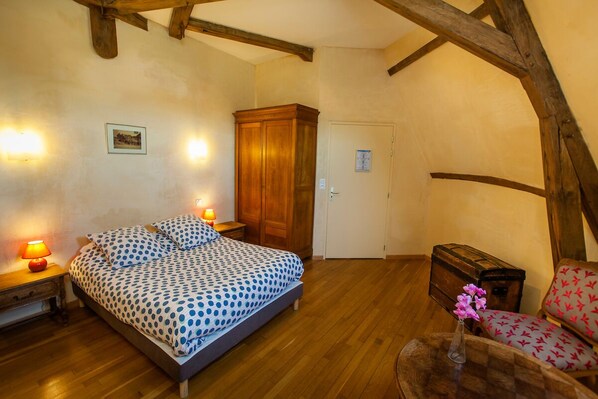 A bedroom with a bed, wooden wardrobe, and a chair.