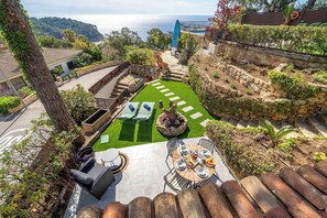 A rooftop garden with a dining table, two lounge chairs, and a surfboard. - Villa Can Toni | Sea Views Private Pool Jacuzzi Air Conditioning Ideal Families (Girona)