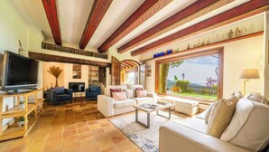 Un salón espacioso con televisor grande, asientos cómodos, chimenea y vistas al exterior.