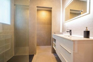 A modern bathroom with a glass shower enclosure, a white vanity with a black soap dispenser, and a mirror reflecting the shower area. - Villa Can Toni | Sea Views Private Pool Jacuzzi Air Conditioning Ideal Families (Girona)
