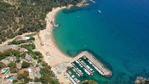 Vista aérea de una zona costera con playa, puerto deportivo y edificios residenciales.