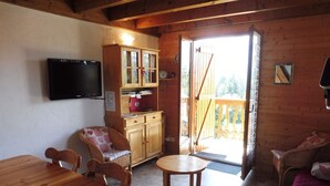 A cozy cabin interior with a wooden dining table, two chairs, a small round table, a television mounted on the wall, and a wooden cabinet with glass doors. - Duplex for 6 with Garage, Near Slopes in Crest-Voland (Crest-Voland)