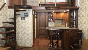 A compact kitchen with a central island, a staircase leading to an upper level, and a dining area with bar stools. - Duplex apartment in the historical center of Odessa (Odessa)