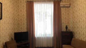 A living room with a flat-screen TV, a round coffee table, a sofa, a cabinet, and a window with sheer curtains. - Duplex apartment in the historical center of Odessa (Odessa)
