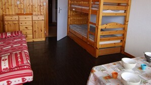 Een kamer met een houten stapelbed, een dressoir en een tafel met kommen.