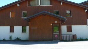 Een houten gebouw met twee verdiepingen, een grote garage deur, meerdere ramen en een klein terras.