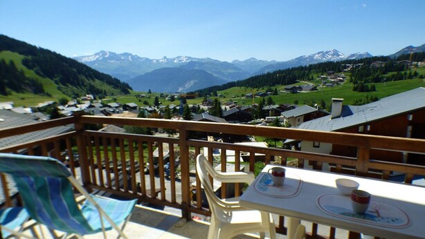 Un balcone con tavolo e sedie affacciato su un paesaggio montano.