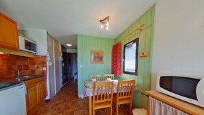 Una cucina compatta con zona pranzo, dotata di microonde, pensili in legno e pavimento piastrellato.