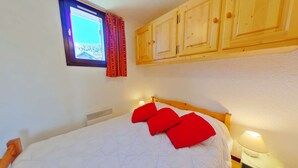 Una camera da letto con un letto, armadietti in legno, una finestra con tende e un comodino con una lampada.
