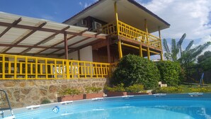 A hotel with a swimming pool, a covered outdoor area, and a stone wall. - Cabin With Ocean and Forest Views (Tubará)