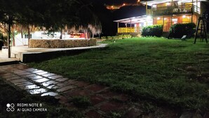 A nighttime view of a building with a covered outdoor seating area and a well-lit lawn. - Cabin With Ocean and Forest Views (Tubará)