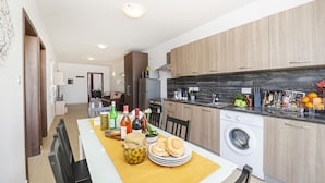 Una cocina moderna con armarios de madera, lavadora integrada y un comedor con una mesa para dos.