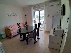Un comedor con una mesa redonda y sillas, un sofá y un refrigerador.