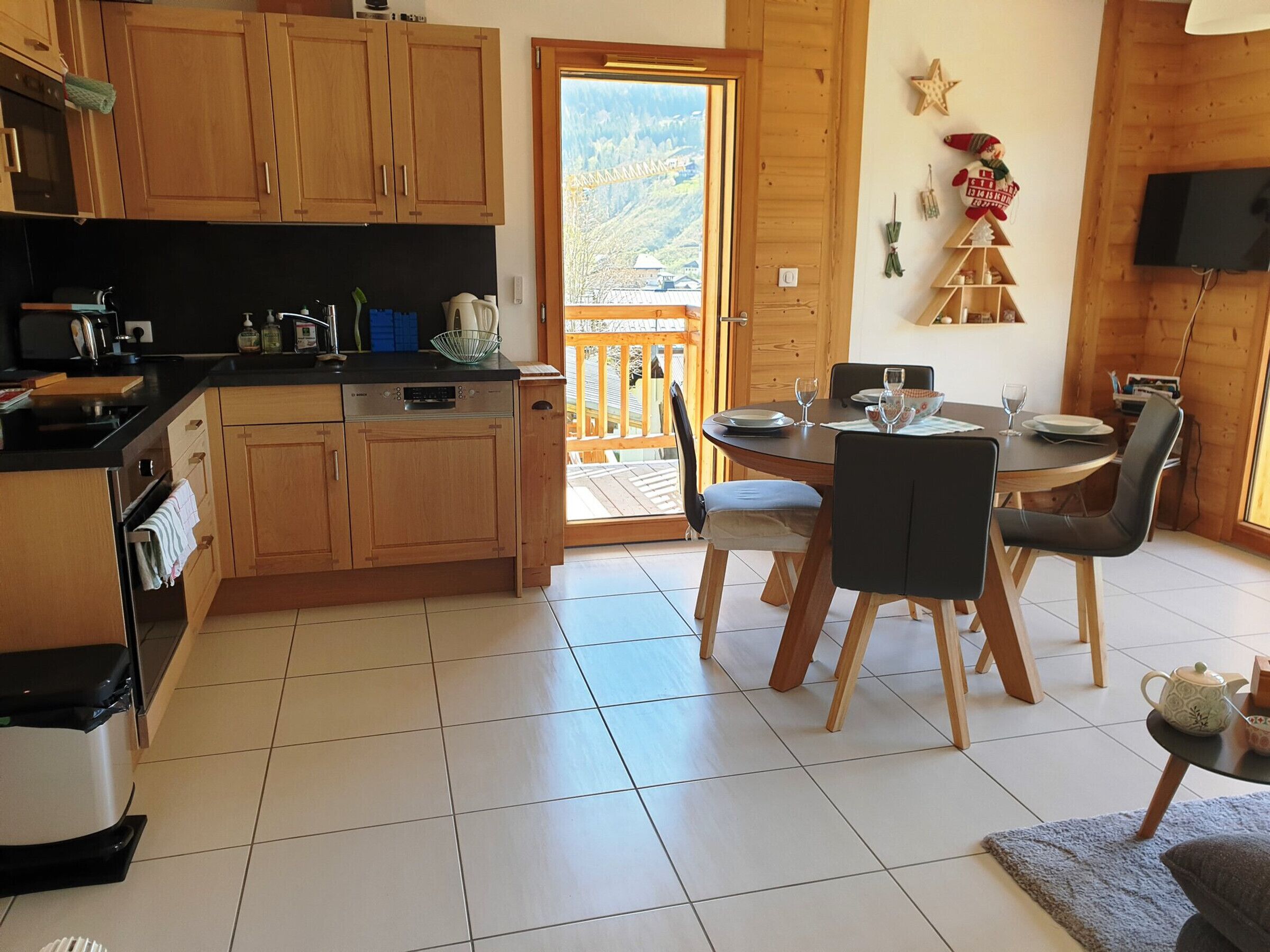 A kitchen with wooden cabinets, a dishwasher, and a dining area with a table and chairs.