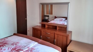 A bedroom with a bed, a wooden dresser, a mirror, and a nightstand.