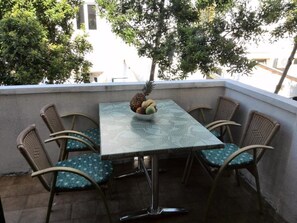 A balcony with a table and chairs, a pineapple, and a bowl of fruit. - Guesthouse Raffaello (Rab)