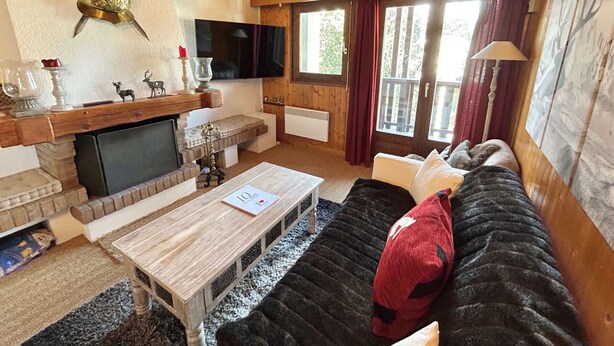 A cozy living room with a fireplace, wooden furniture, and a television. - Charming 3-Room Apartment with Mezzanine, 1km from Ski Lifts - Megève (Megève)