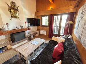 Ein gemütliches Wohnzimmer mit Kamin, Holzmöbeln und einem Fernseher.