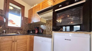 A kitchen with wooden cabinets, a Bosch dishwasher, and a Brandt refrigerator. - Charming 3-Room Apartment with Mezzanine, 1km from Ski Lifts - Megève (Megève)
