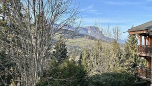 A mountain view from a wooden cabin with a balcony overlooking a forested valley and distant mountains. - Charming 3-Room Apartment with Mezzanine, 1km from Ski Lifts - Megève (Megève)