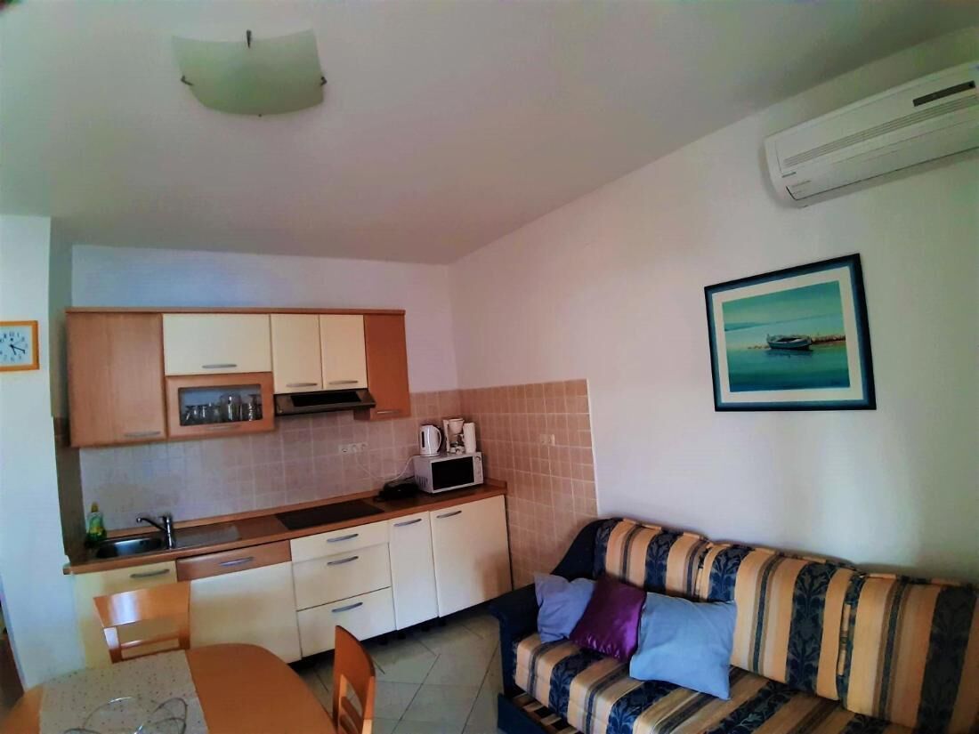 A compact kitchen with a dining area, a sofa, and a framed picture on the wall.