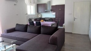 Una sala de estar moderna con un sofá modular, una mesa de centro de vidrio y un comedor con mesa y sillas.