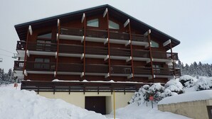 Un immeuble en bois à plusieurs étages, doté de balcons, et entouré de neige.
