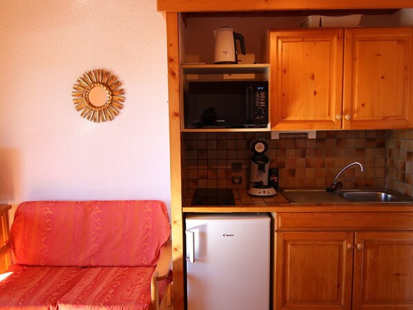 A compact kitchenette with a microwave, coffee maker, and a refrigerator.