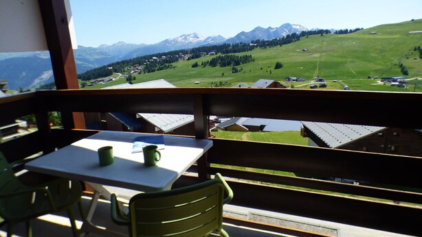 Un balcon avec une table et des chaises donnant sur un paysage montagneux.