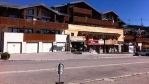 Un hôtel à plusieurs étages doté de balcons, avec un restaurant au rez-de-chaussée et un télésiège visible au loin.