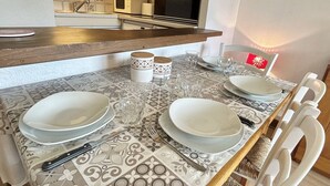 A dining area with a table set for two, featuring patterned tablecloths, white plates, cutlery, and glassware. - Cozy Studio with Balcony, Near Ski Lift, Pool & Tennis, Megève - Sleeps 4 (Megève)