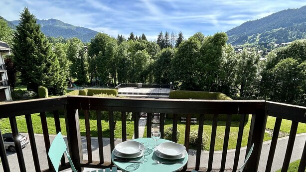A balcony with a table and chairs, overlooking a mountainous landscape. - Cozy Studio with Balcony, Near Ski Lift, Pool & Tennis, Megève - Sleeps 4 (Megève)