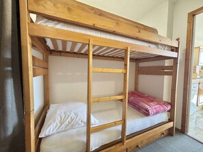 A bunk bed with a wooden frame, white bedding, and a pink blanket. - Functional studio cabin for 6 at the foot of the slopes - Parking included (Notre-Dame-de-Bellecombe)
