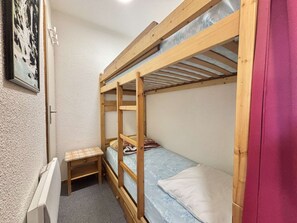 A bunk bed room with a small table and a radiator. - Functional studio cabin for 6 at the foot of the slopes - Parking included (Notre-Dame-de-Bellecombe)