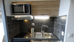 A compact kitchen with a microwave, stove, sink, and a kettle. - Cozy studio Les Saisies 4 people (Les Saisies)