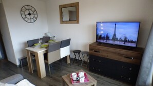 A compact living space with a dining area, a television, a mirror, and a small table with a tray. - Cozy studio Les Saisies 4 people (Les Saisies)
