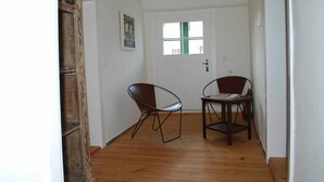 A hallway with wooden flooring, a white door with a window, and two chairs. - Alte Schmiede (Bad Griesbach im Rottal)