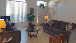 A living room with a sofa, two lamps, a table, and a staircase. - Extra Spacious Florida Villa, 15 mins to Disney. (Davenport)