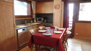 A wooden kitchen with a dining table set for six, a microwave, and a sink. - Cozy 2-Bedroom Apartment with Cabins in Crest-Voland - Near Slopes, Sleeps 6 (Crest-Voland)