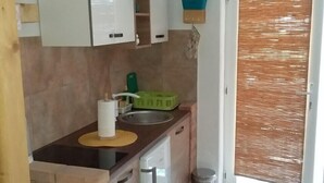 Una cocina compacta con un lavamanos, un escurreplatos y un pequeño cubo de basura.