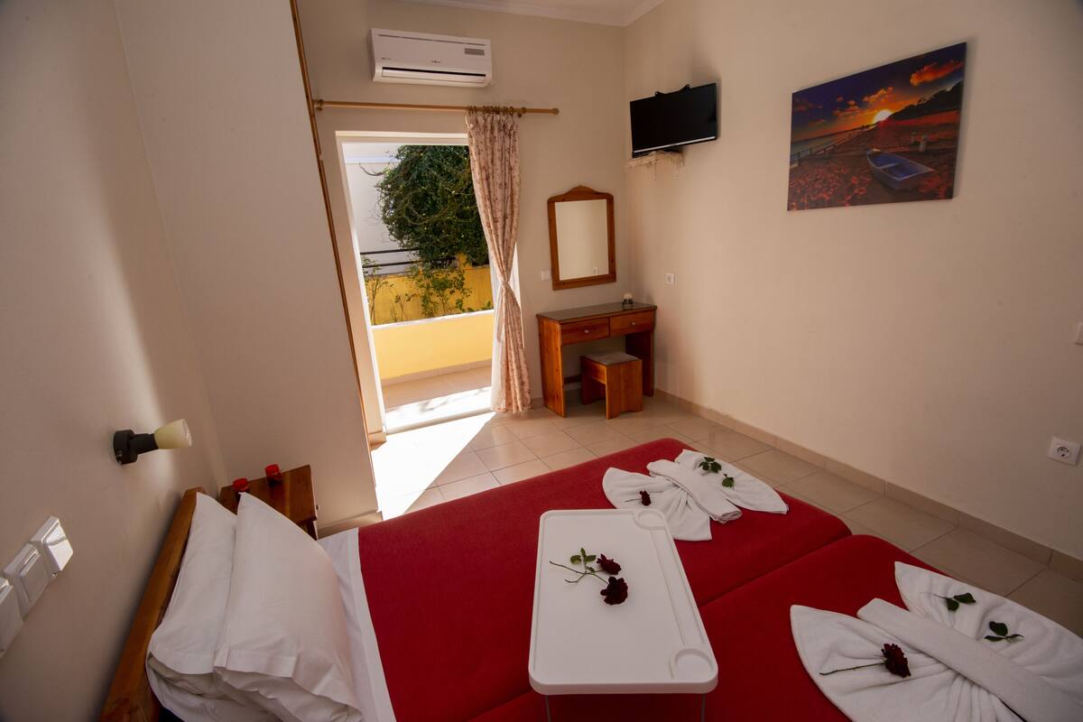 Una habitación de hotel con una cama, un escritorio, un televisor y un cuadro de un atardecer.