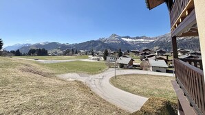 Un pueblo de montaña con casas de madera tradicionales, cielo despejado y un camino sinuoso que lleva al pueblo.