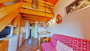 Una cabaña acogedora con habitación en loft, comedor y sala de estar con un sofá rojo estampado.