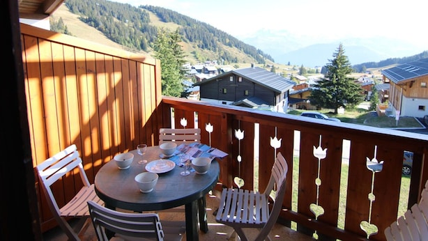 Una terraza de madera con una mesa dispuesta para comer, con vistas a un paisaje montañoso.