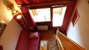 Una habitación acogedora con un sofá estampado, un banco de madera y una mesita con una revista.