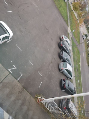 A parking lot with multiple cars parked in designated spaces, a pedestrian crossing, and a grassy area with trees. - Pension am Messegelände (Magdeburg)
